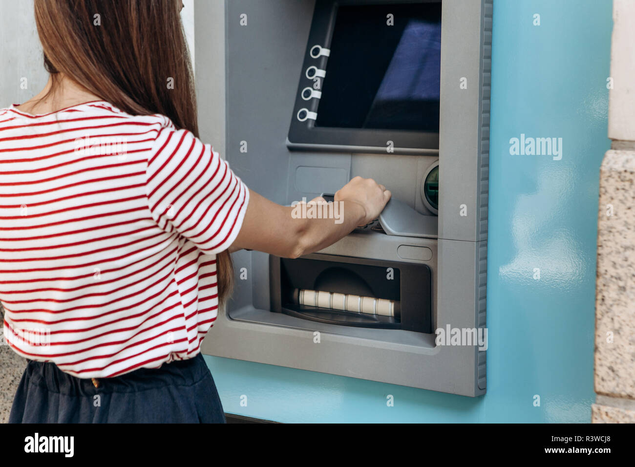 The tourist withdraws money from the ATM for further travel. Finance, credit card, withdrawal of money. Life style. Journey. Vacation. Grabs a card from the ATM. Stock Photo