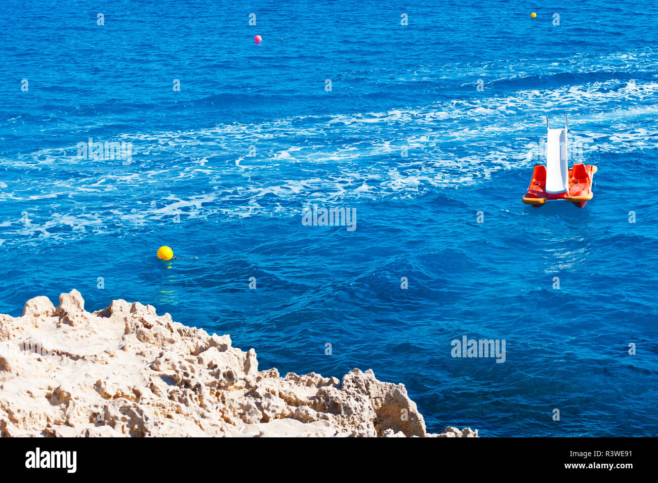 Image of calm sea surface. Closeup of one orange paddleboat in deep blue water against foamy trace on the background. Warm day in fall. Concept of lei Stock Photo