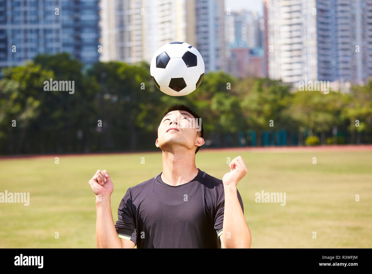 asian soccer football player practicing ball skill on outdoor field Stock Photo