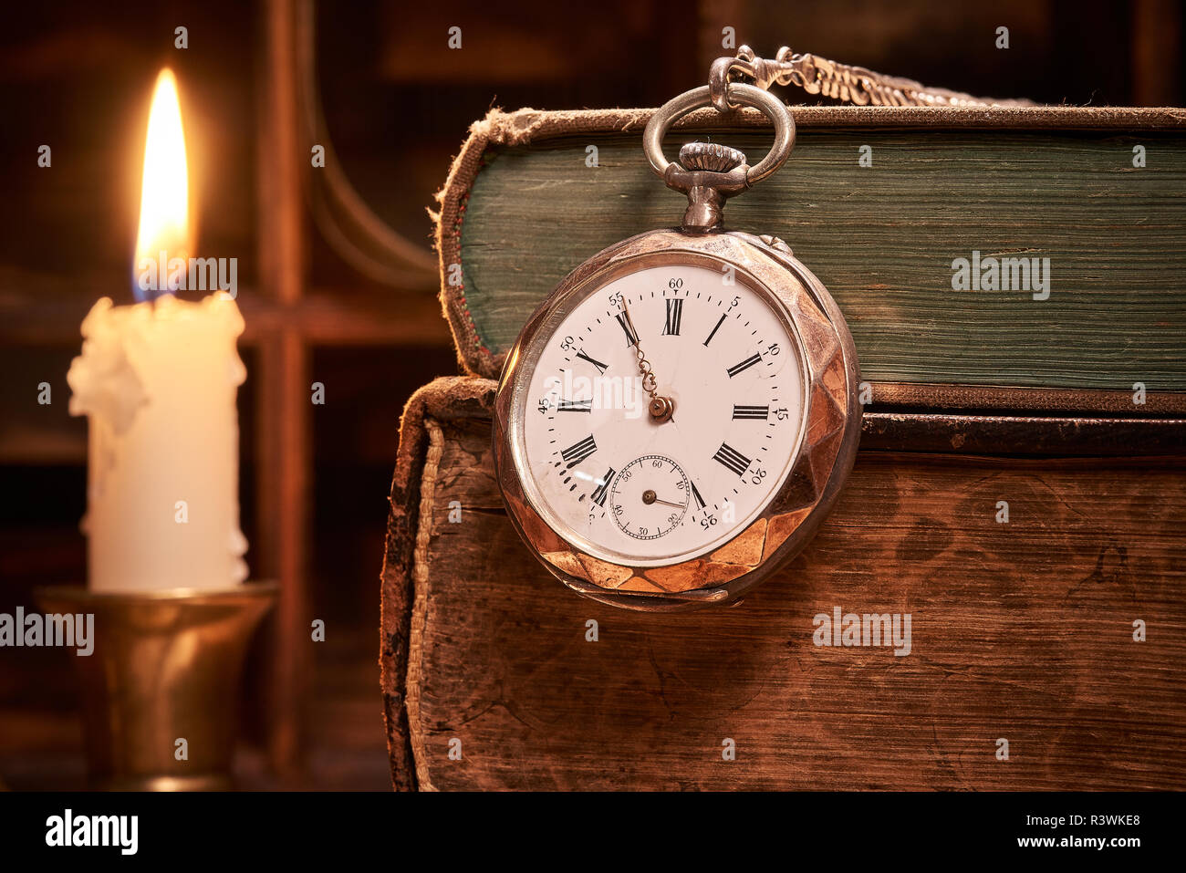 Old books with antique pocket watch by candlelight Stock Photo