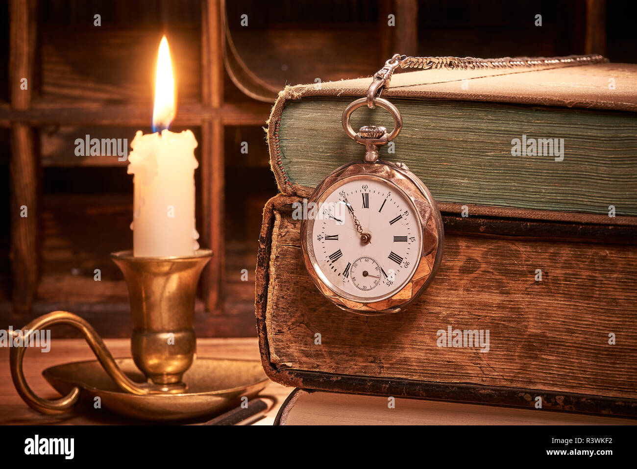 Old books with antique pocket watch by candlelight Stock Photo