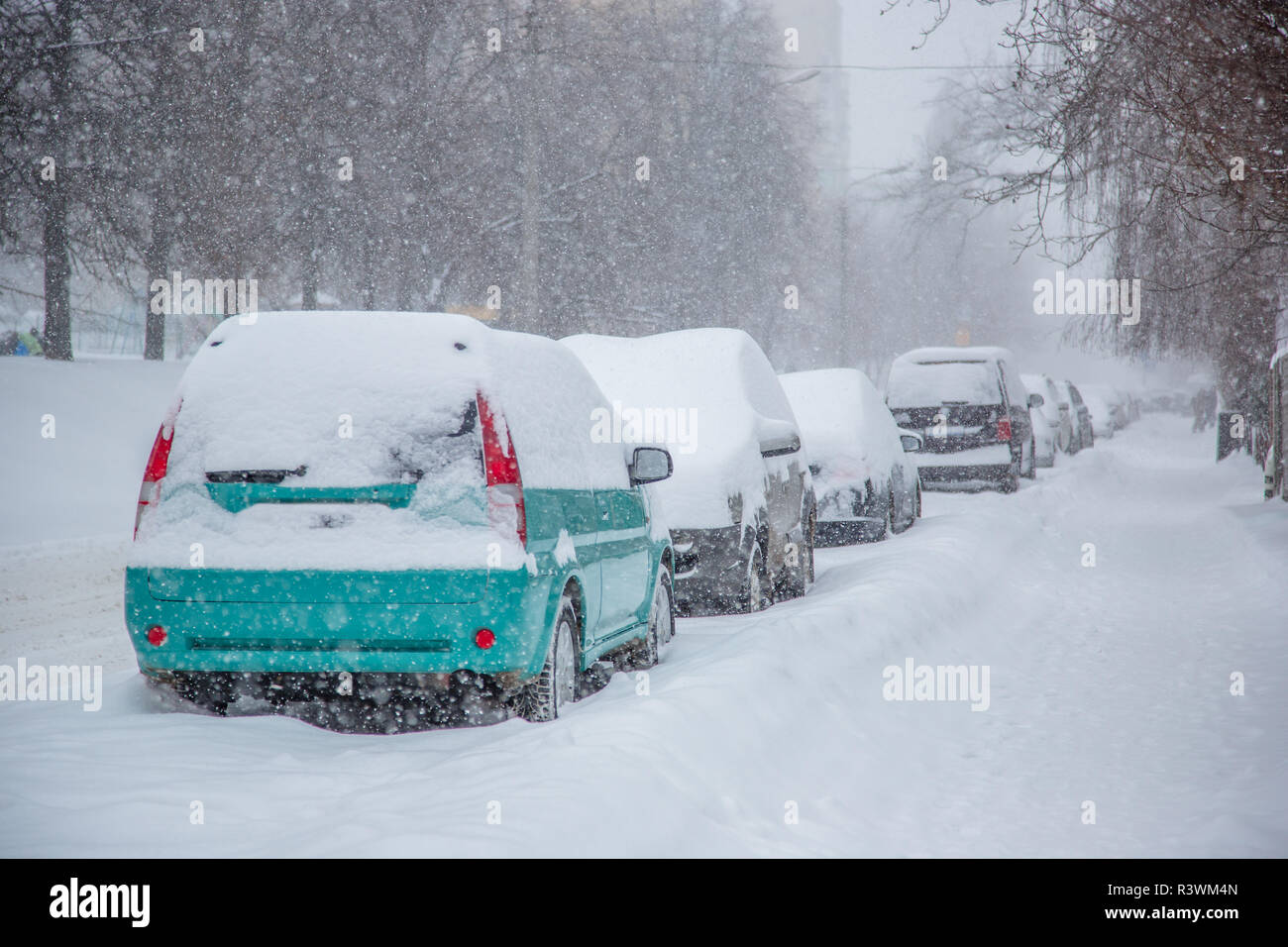 Vehicles covered with snow in a winter blizzard in the parking lot ...