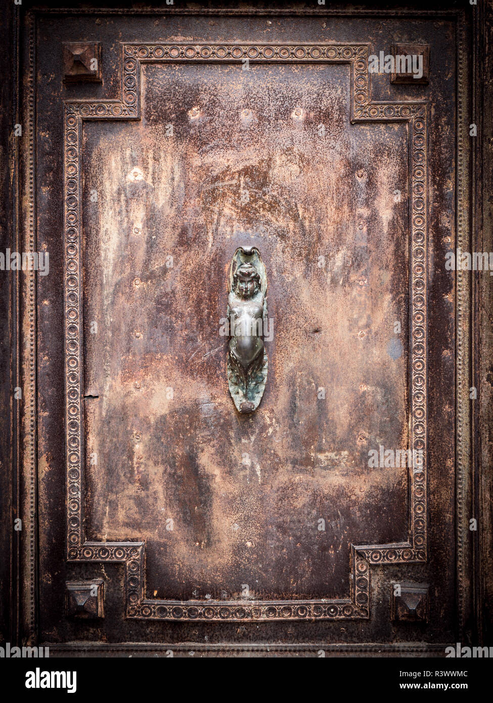 Mermaid-shaped handle of an ancient portal of an old building. Stock Photo