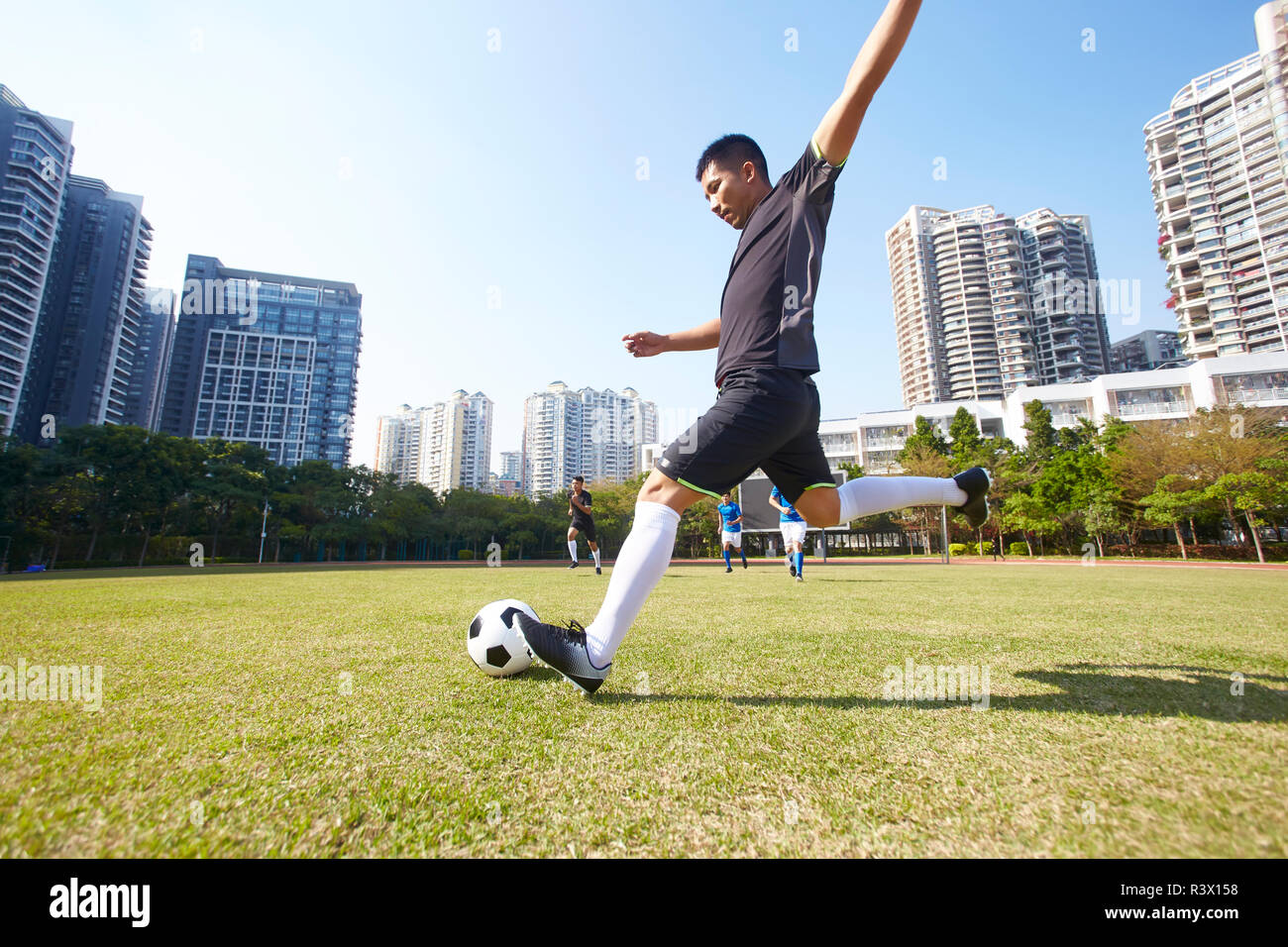 young asian soccer football player shooting the ball during match Stock Photo