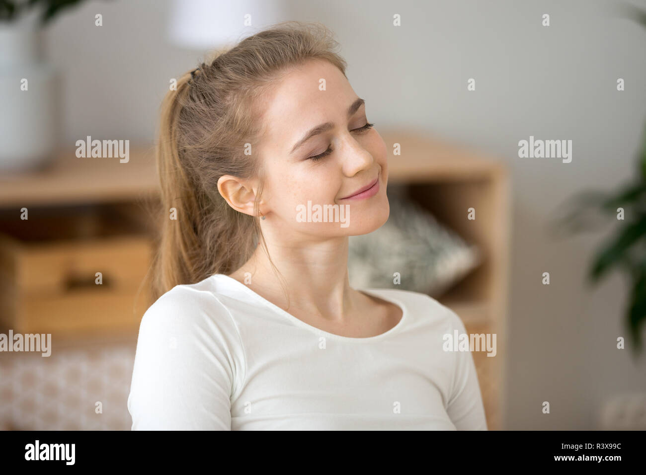 Happy young girl with eyes closed dreaming at home Stock Photo