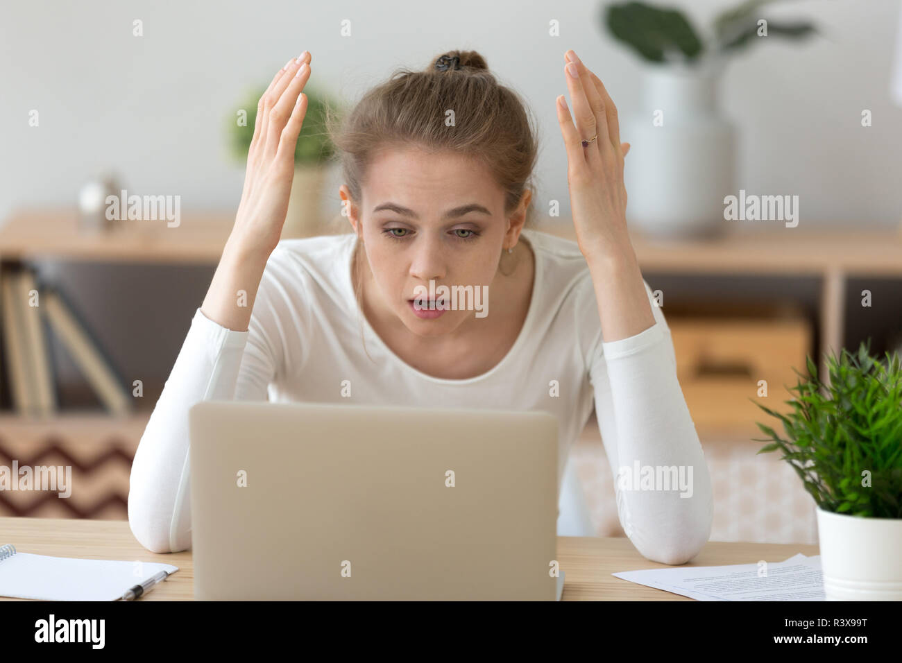 Frustrated girl reading shocking news at laptop Stock Photo
