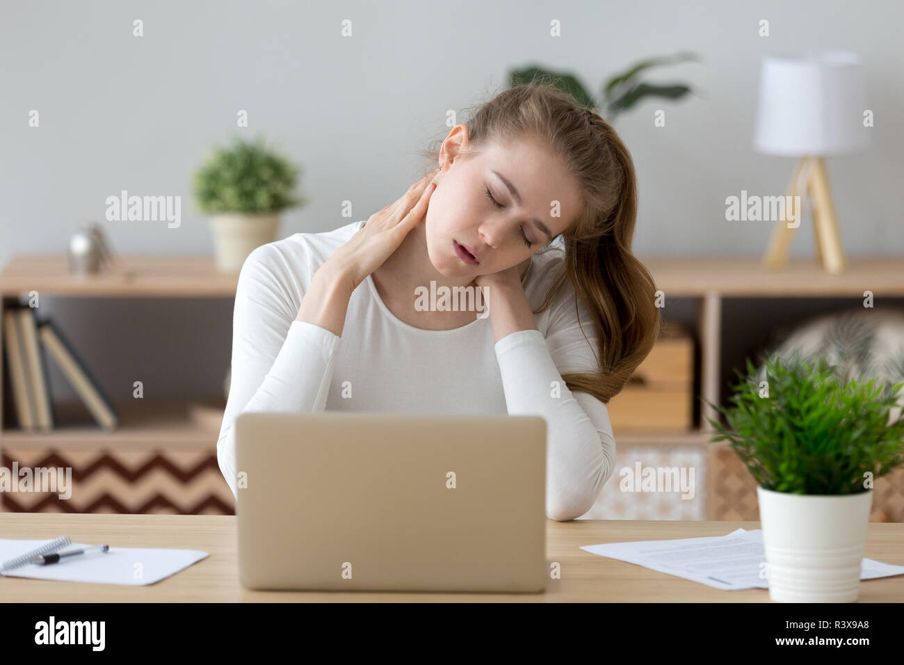 Tired girl massaging neck suffering from back pain Stock Photo