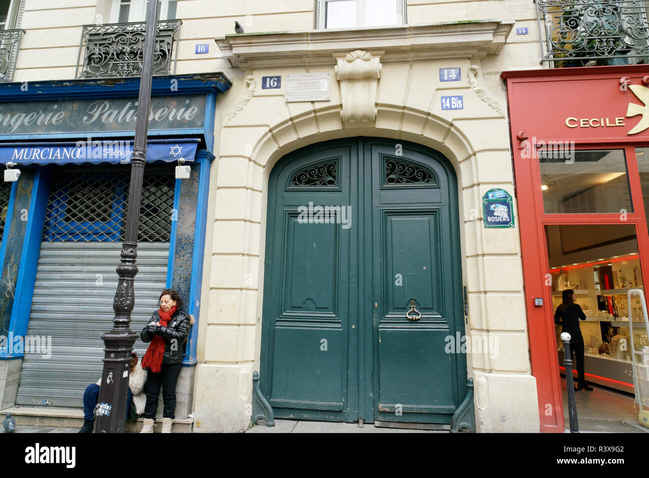 A house and shops on the Rue des Rosiers in the Marais, Paris. A plaque  lists Jews who lived there, who were deported and killed during World War II. Stock Photo