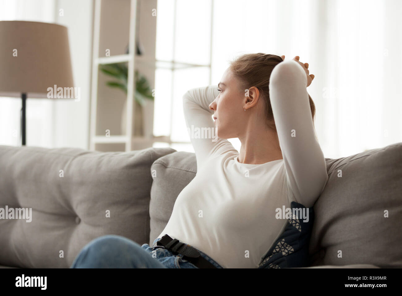 Young female relax on couch looking in distance thinking  Stock Photo