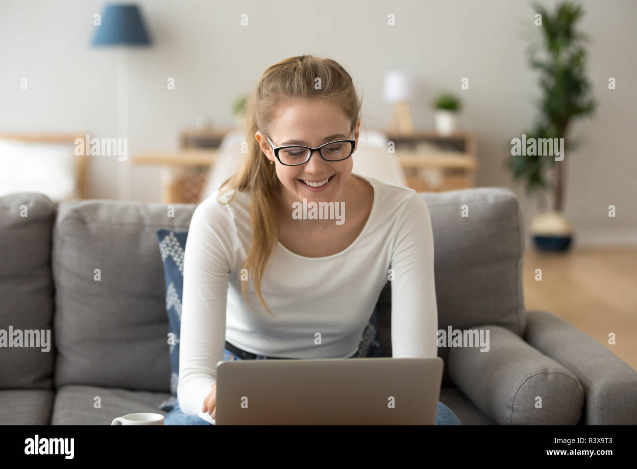 Happy female in glasses using laptop at home Stock Photo