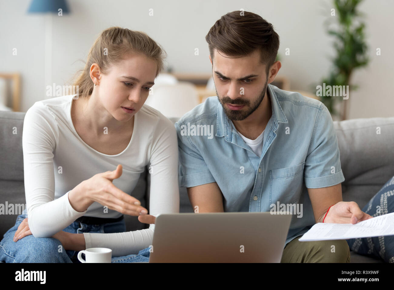 Concerned couple use laptop considering financial bills Stock Photo