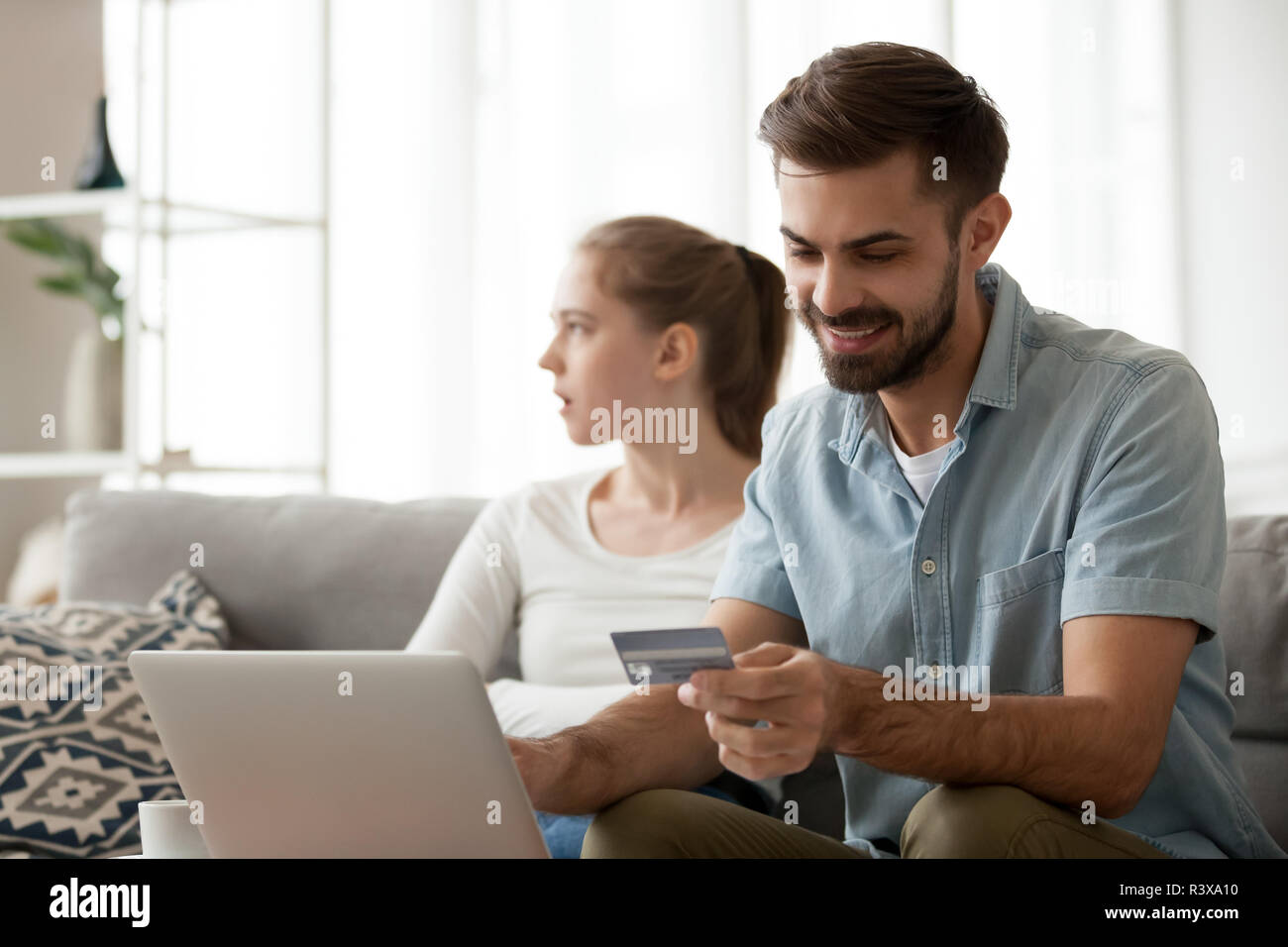 Excited husband shopping online not paying attention to wife Stock Photo