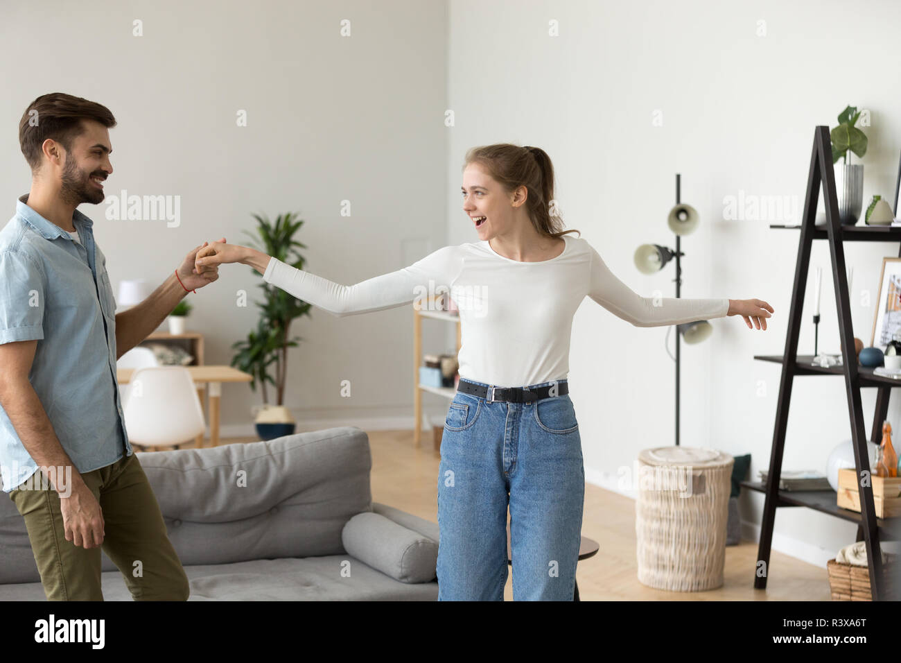Happy couple have fun dancing in living room together Stock Photo
