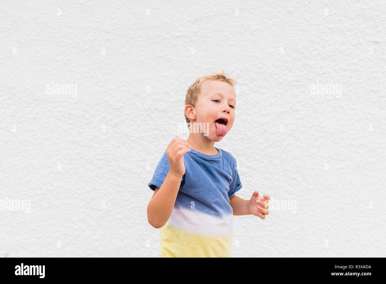 Blond boy making funny faces on white background. Stock Photo