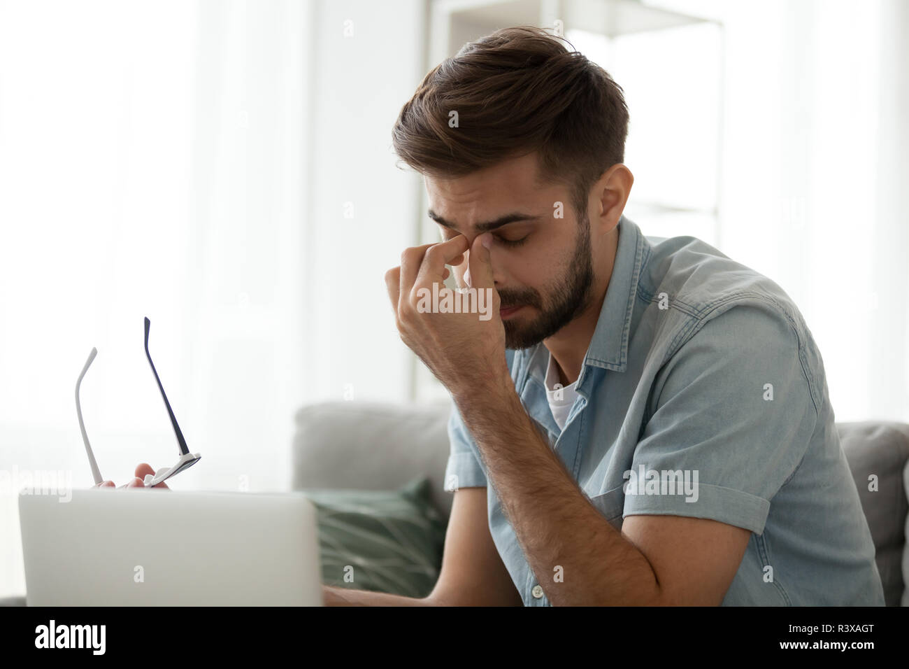 Tired man take off glasses suffering from blurry vision Stock Photo