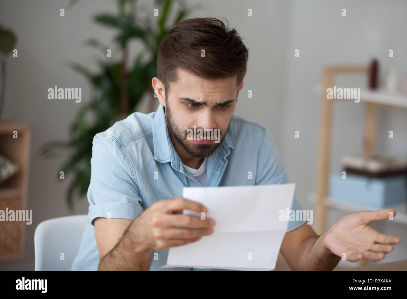 Confused male reading letter shocked by news Stock Photo