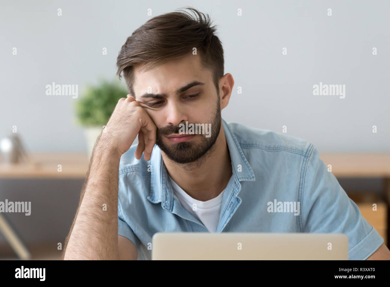 Lazy man feel unmotivated sitting near laptop at home Stock Photo