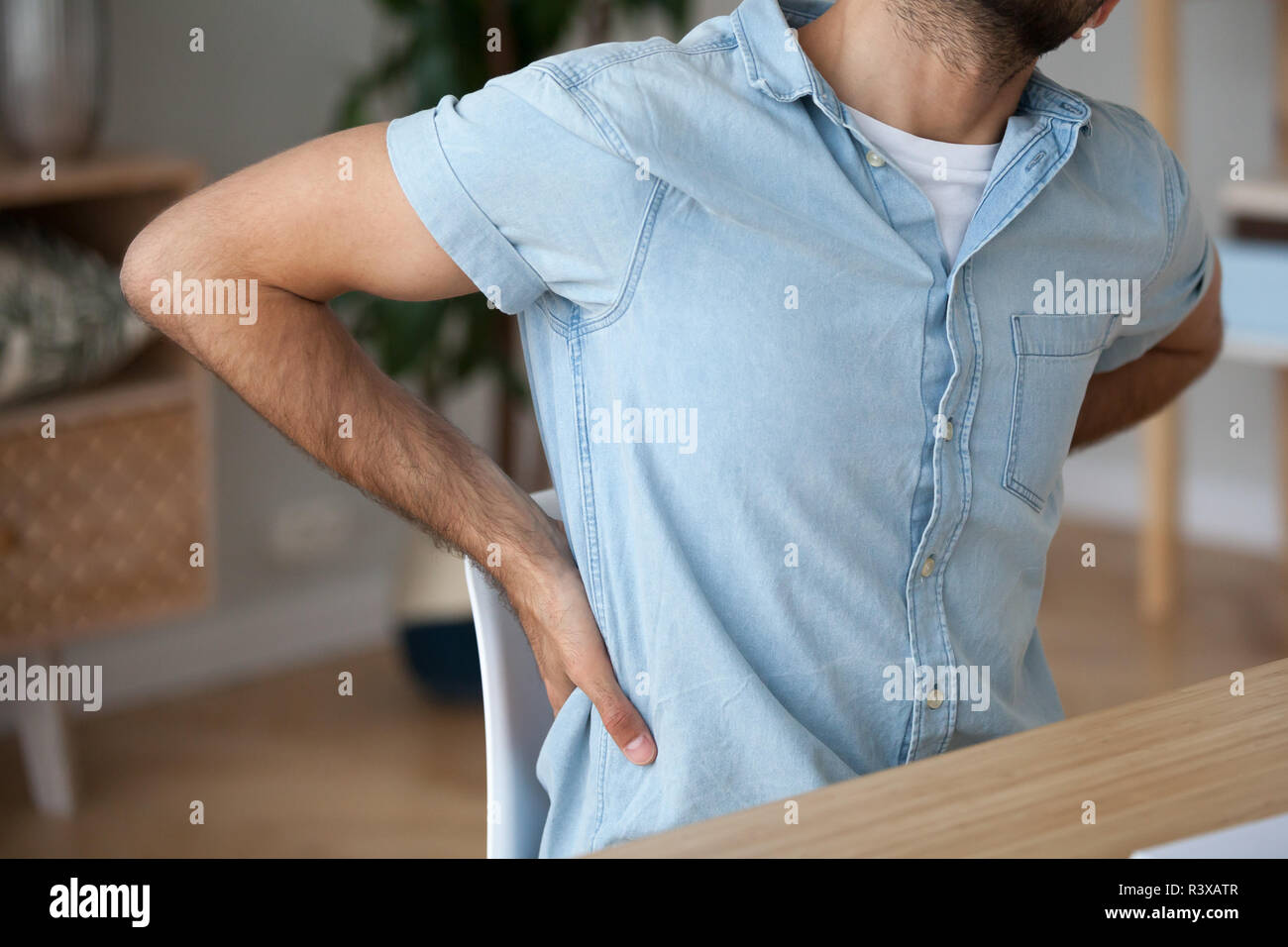Hurt male stretch in chair suffering from back pain Stock Photo Alamy