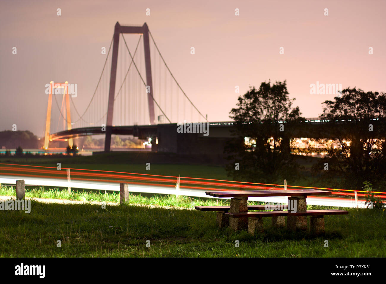 A rather unusual resting place near the famous suspension bridge in Emmerich, Germany. Long exposure with light trails, focus on foreground. Stock Photo