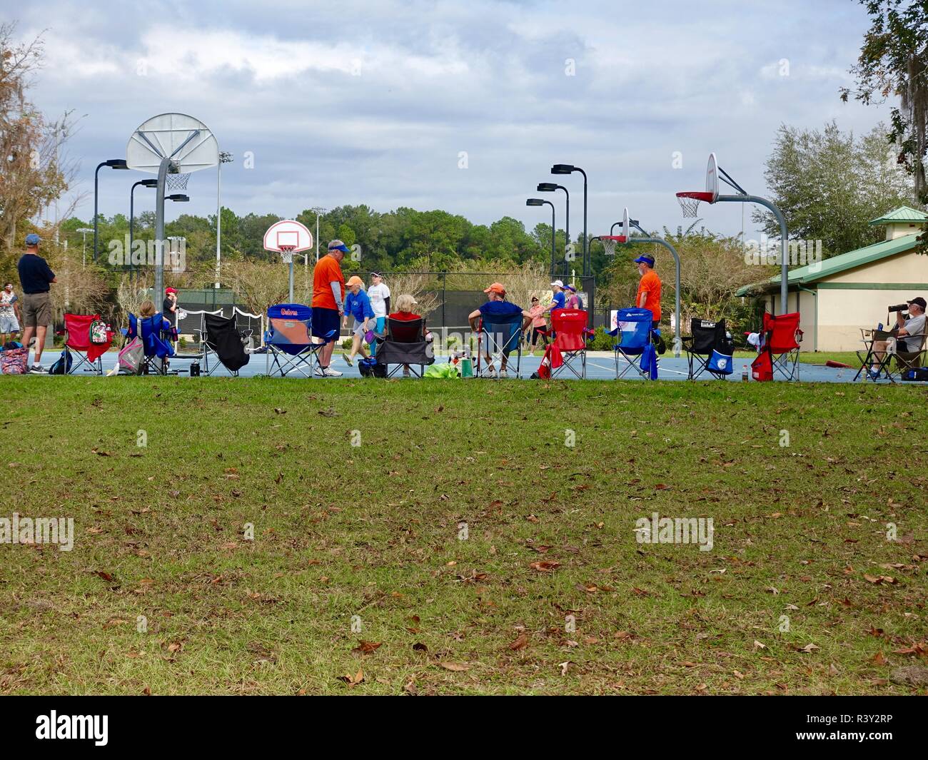 Large group of mature people gathered together to watch and play Pickleball, a paddle sport, on a fine, late autumn morning in North Florida, USA. Stock Photo