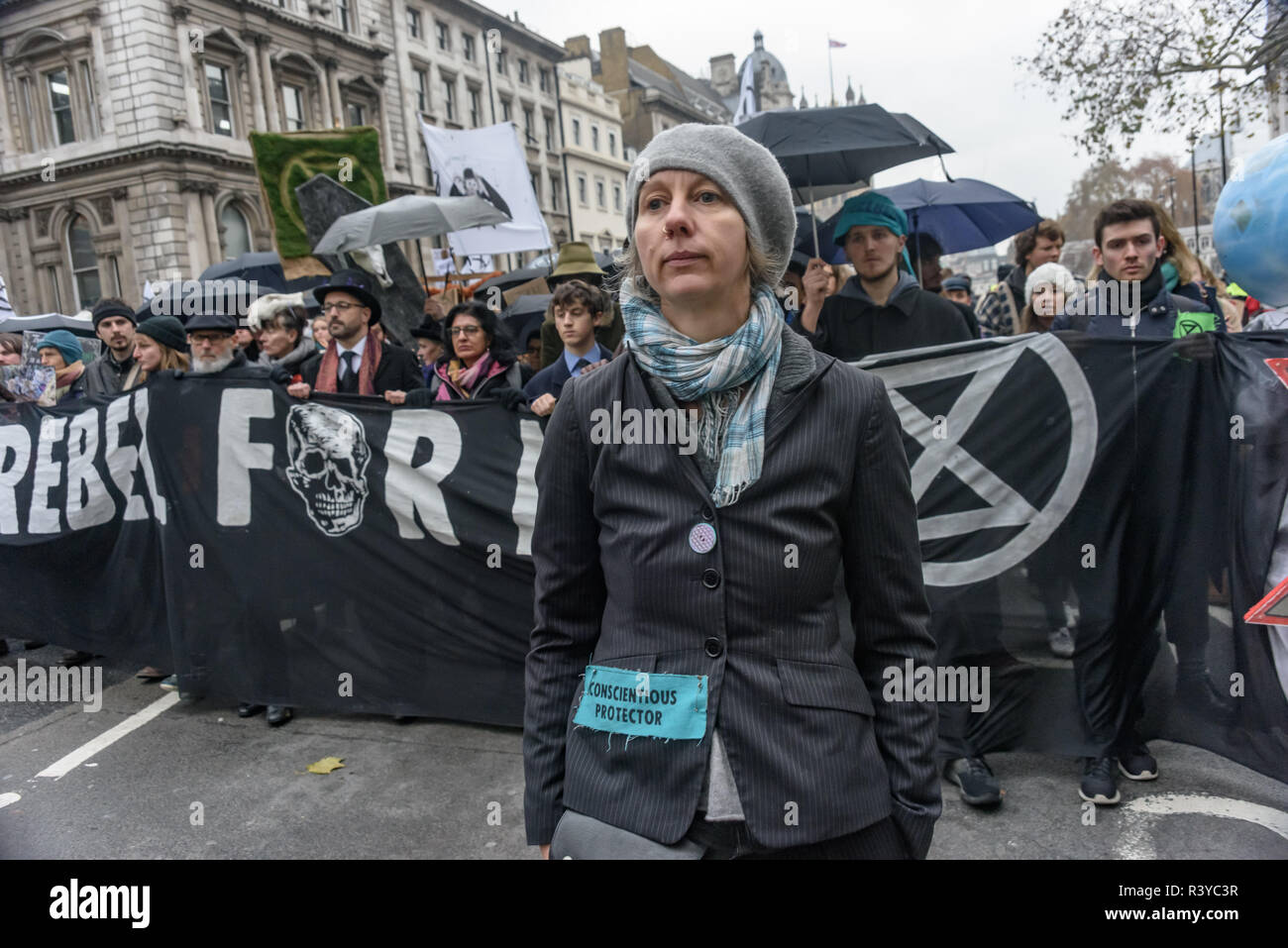London, UK. 24th November 2018. After being prevented from burying their coffin Extinction Rebellion campaigners led by Gail Bradbrook walk up Whitehall in procession behind it, led by drummers and a trumpeter. They walked slowly up Whitehall and stop briefly to sit down in the road in silence when the coffin reached Downing St. When the procession moved on, others lay in the road to form the Extinction Rebellion Symbol for some minutes, before moving to join the rest on their way down The Mall to Buckingham Palace. emorial. Pet Stock Photo