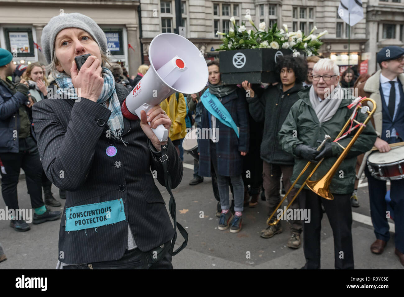 London, UK. 24th November 2018. Gail Bradbrook speaks as the Extinction Rebellion funeral procession pauses in Whitehall to allo everyone to catch up. She tells them that they are going to walk down The Mall on their way to Buckingham Palace. A few officers made a half-hearted attempt to stop them, but were called off and the procession went on its intended way. emorial. Peter Marshall/Alamy Live News Stock Photo