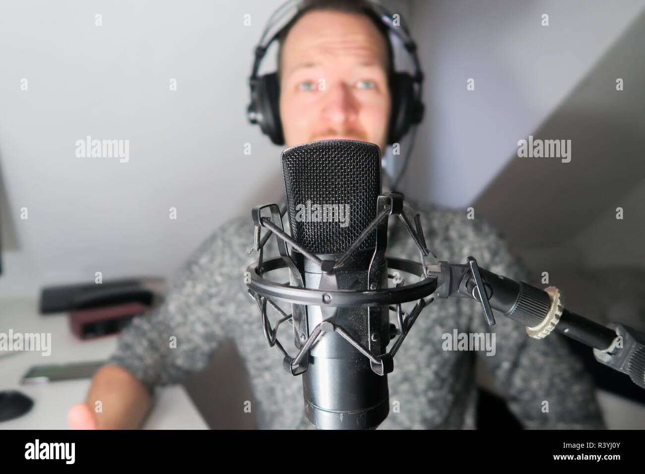 Young male behind condenser microphone radio podcast host voice recording Stock Photo