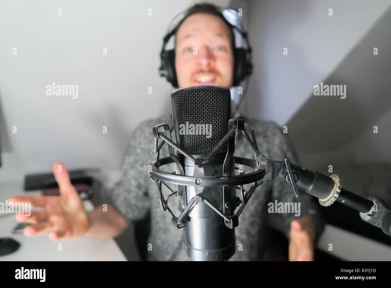 Young male behind condenser microphone radio podcast host voice recording Stock Photo
