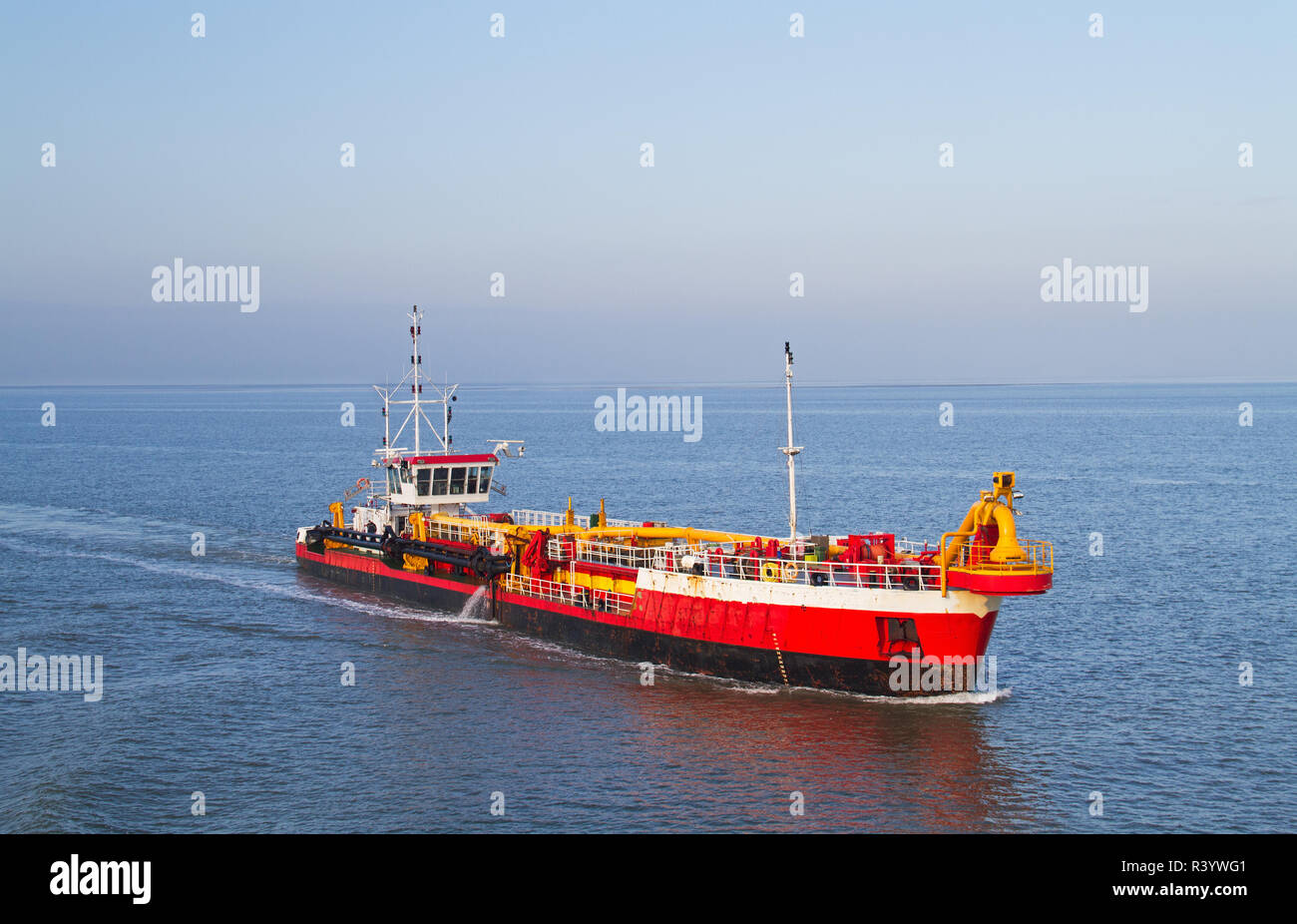 Red dredging vessel working on sea, removing sediment in a waterway Stock Photo