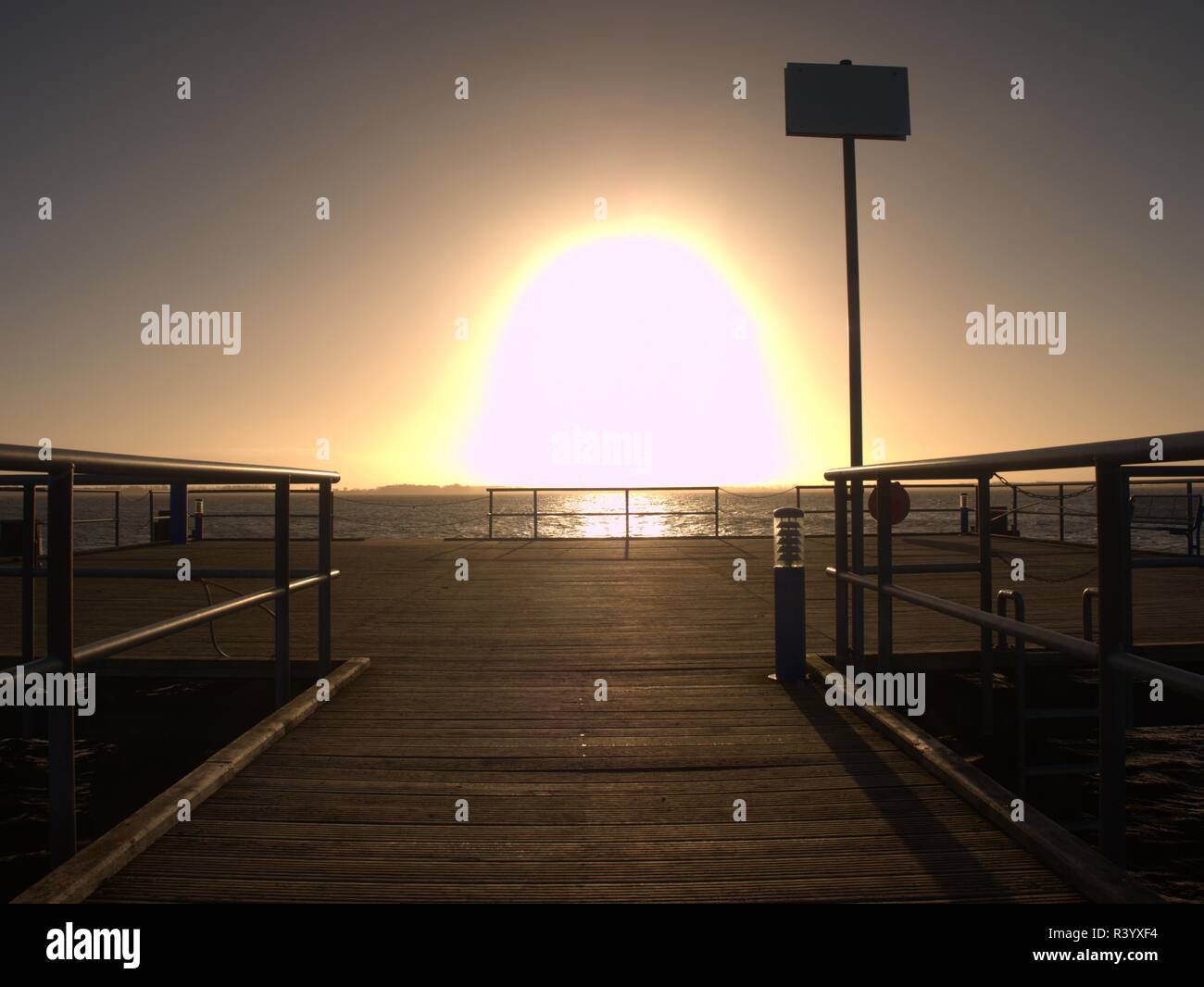 Pier at horizon  goes into the misty sea. Depression dark atmosphere. Touristic mole wet wooden floor above sea. Stock Photo