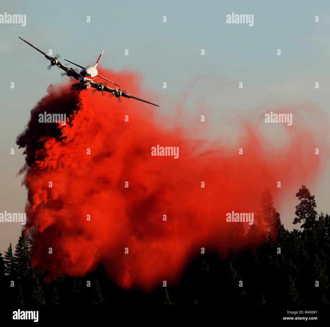 Aerial assault onto a forest fire with RED fire retardant. Stock Photo