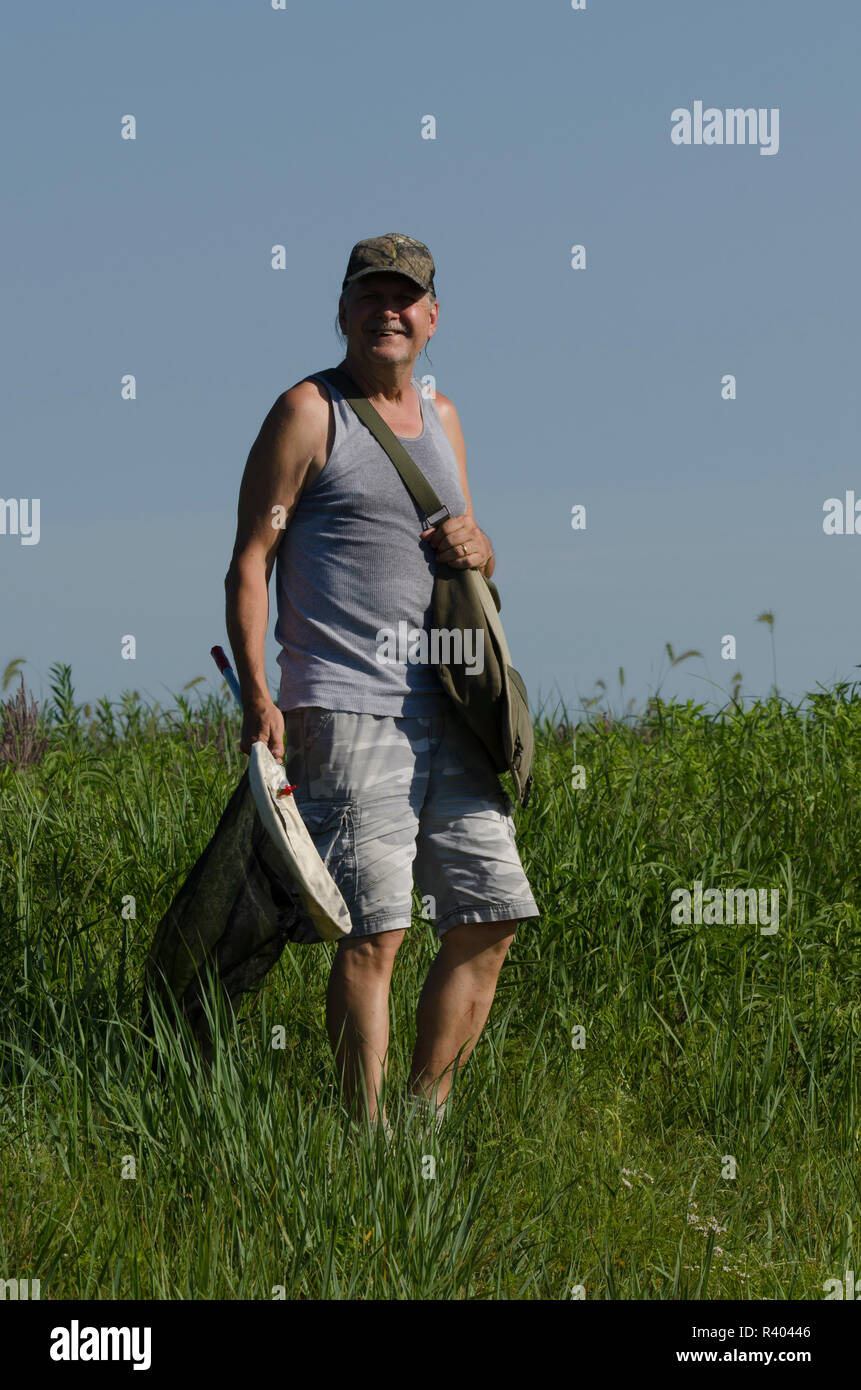 Older man with butterfly net and collecting  butterflies on an Oklahoma prairie Stock Photo