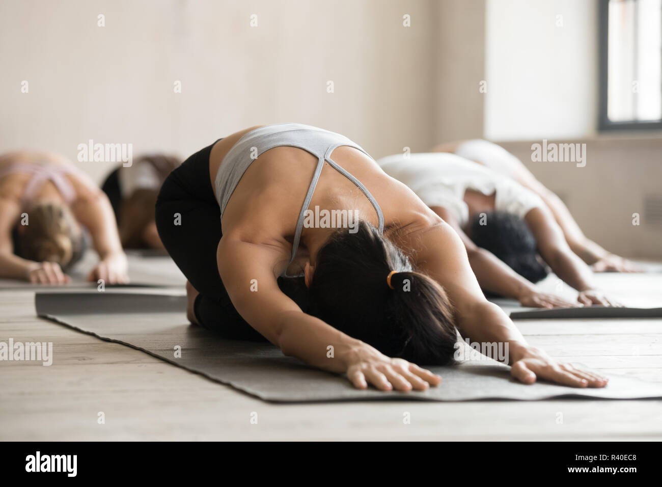 Group of sporty people practicing yoga lesson, doing Child exerc Stock Photo