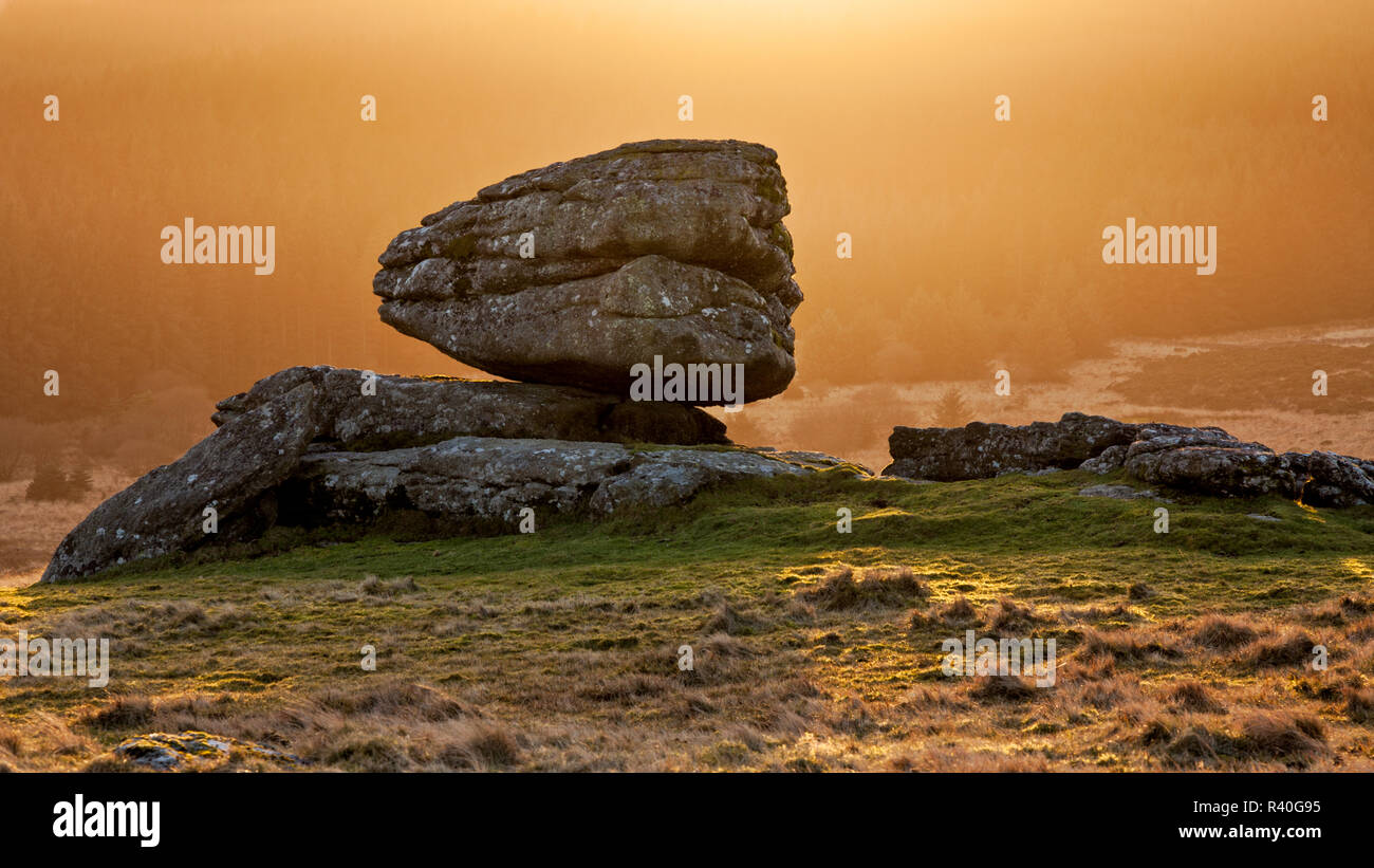 The backlit logan stone at Thornworthy Tor, Dartmoor national park, England Stock Photo
