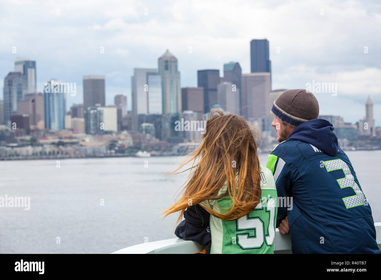 USA, Washington State, Seattle. Passengers on a ferry approaching downtown Seattle, wearing shirts supporting the Seattle Seahawks football team. Stock Photo