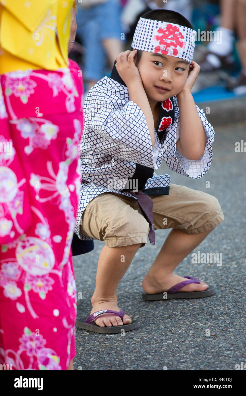 USA, Washington State, Seattle. Young boy in traditional Japanese attire covering his ears as drums play. Stock Photo