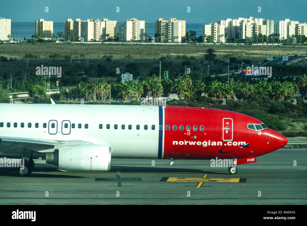 Alicante Airport, Boeing aircraft, Norwegian Airlines plane on tarmac and buildings at seaside Stock Photo