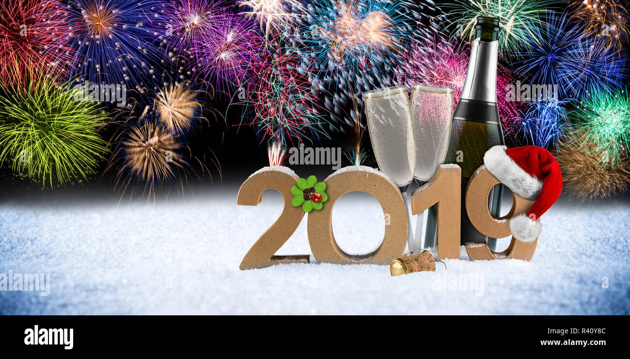 happy new year 2019 number with santa hat four leaf clover champagne bottle glass in front of colorful fireworks pyrotechnic panorama snow background Stock Photo
