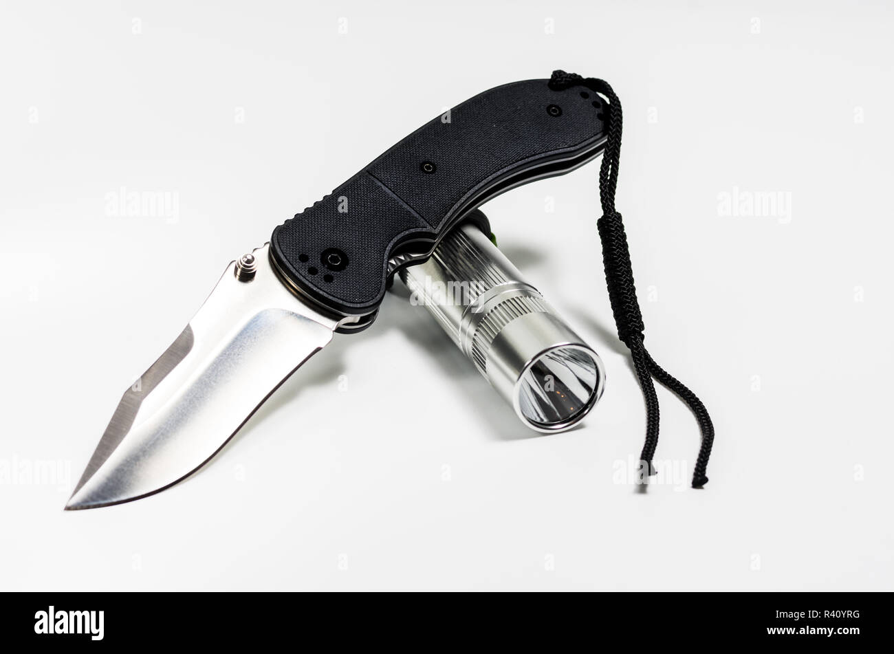 A flashlight and a knife on a white background. Front view Stock Photo