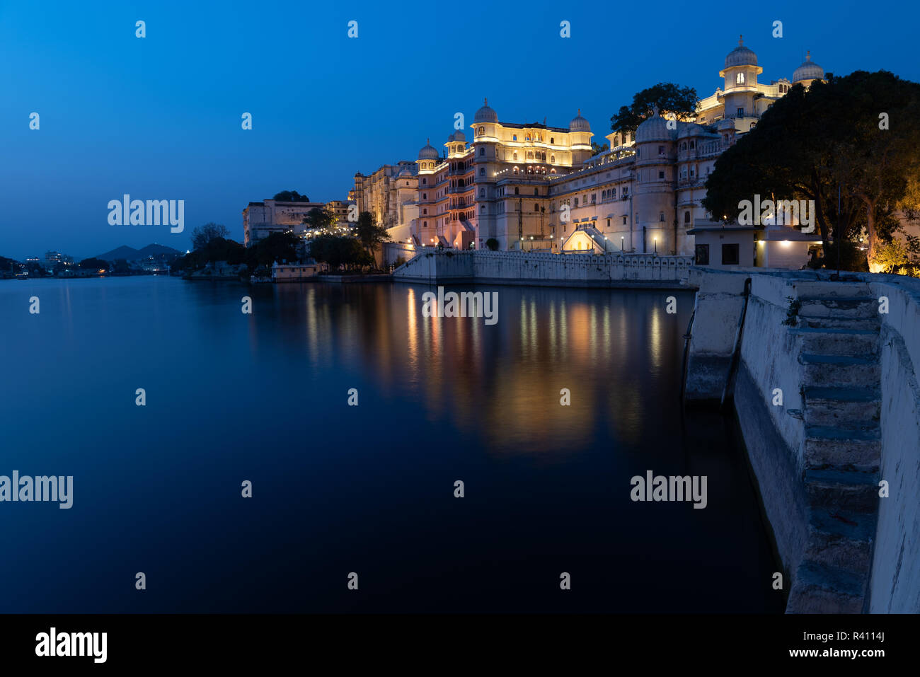 View of Fateh Prakash Palace overlooking and reflecting in the beautiful Lake Pichola by night. Udaipur, Rajasthan, India Stock Photo