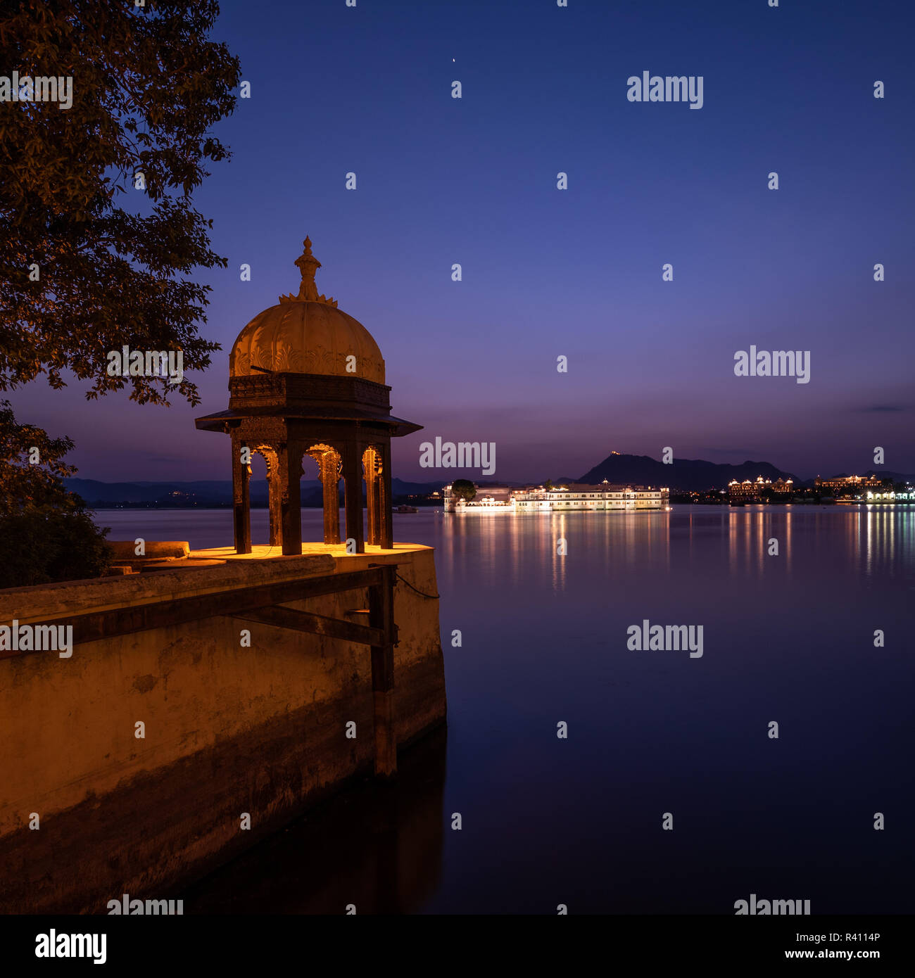 An ornate Chhatri or Canopy typical of Rajasthani architecture at night with Lake Pichola in the background. Stock Photo