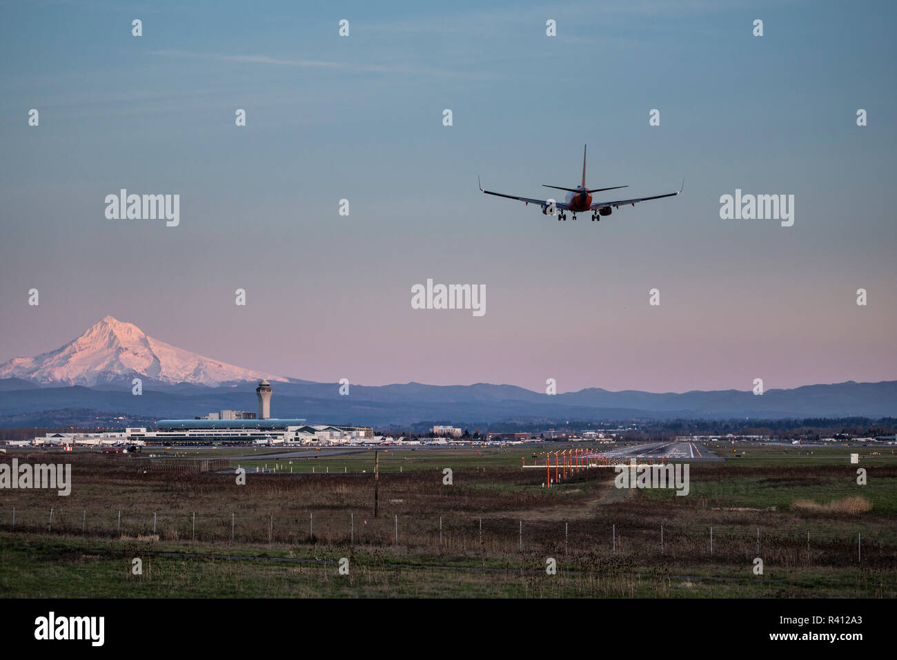 Portland, Oregon, USA. Commercial aircraft on final approach at PDX airport with Mount Hood in the background. Stock Photo