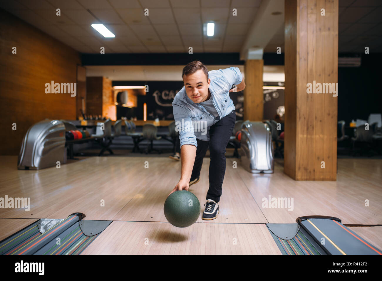 Male bowler throws ball on lane, front view. Bowling alley player, throwing in action, classical