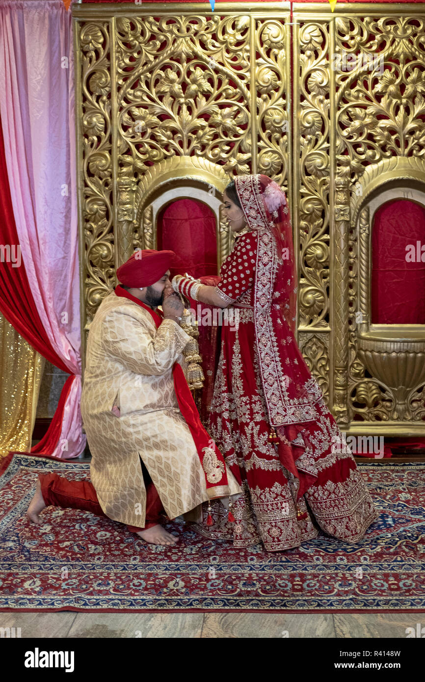 a sikh bride and groom pose for their wedding photographer in a temple after their wedding ceremony in queens new york city R4148W