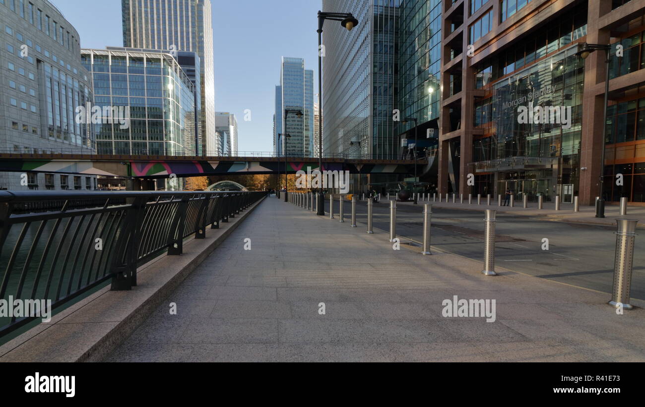 Early Sunday morning in Canary Wharf in London, with dlr train going passed and rear empty bank street. Nice day with blue sky and some reflection. Stock Photo