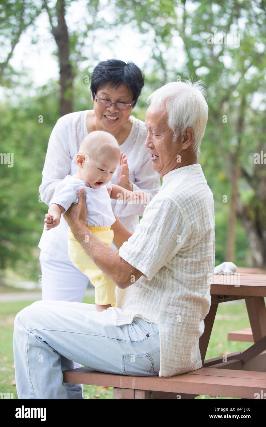 chinese grandfather and grandmother playing with baby grandson at