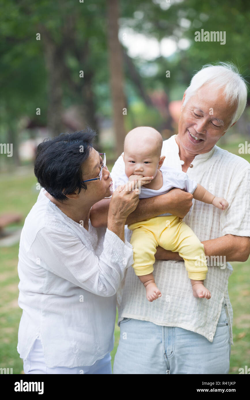 chinese grandfather and grandmother playing with baby grandson at