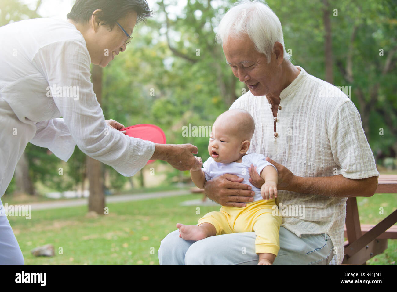 chinese grandfather and grandmother playing with baby grandson at