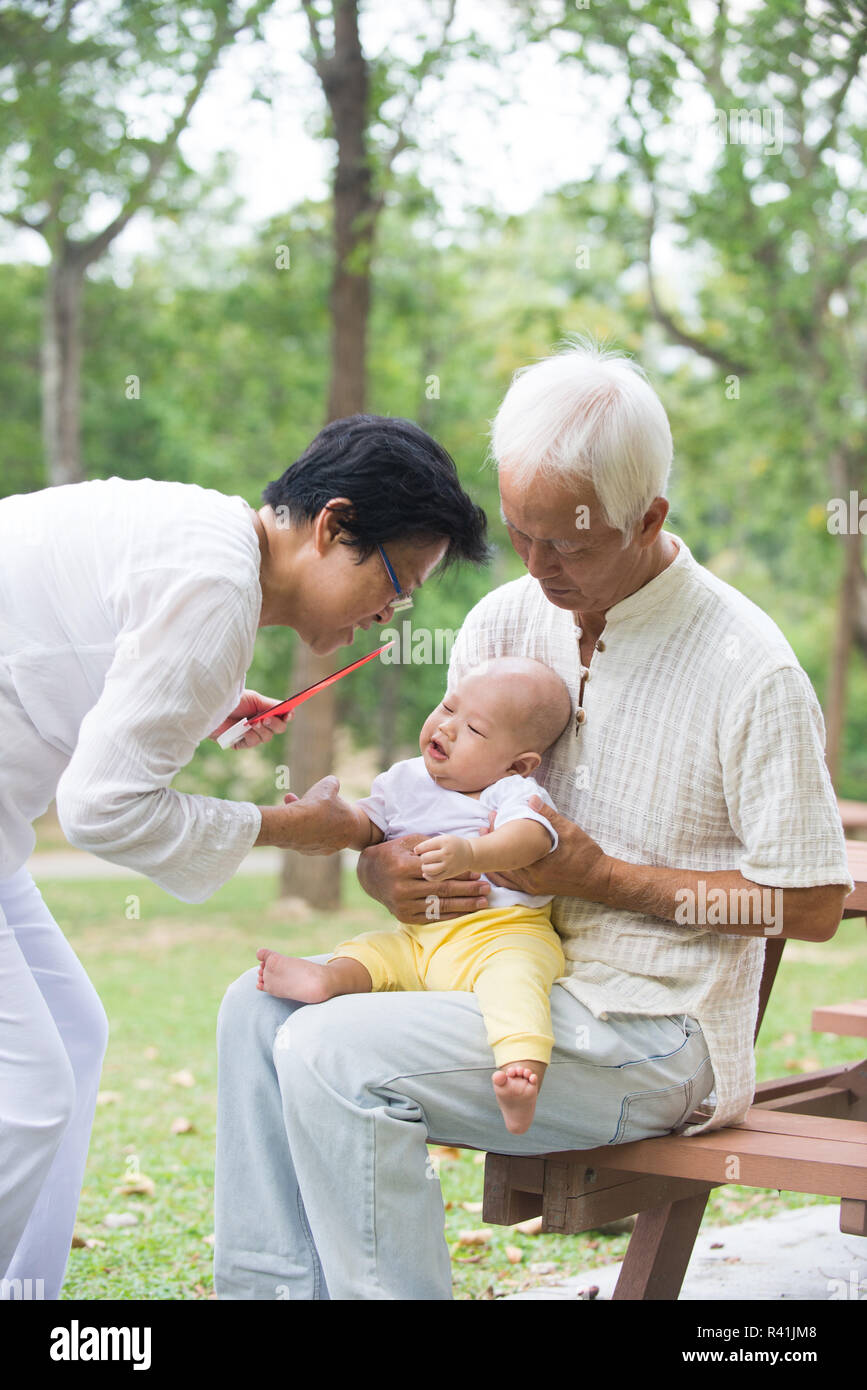 chinese grandfather and grandmother playing with baby grandson at
