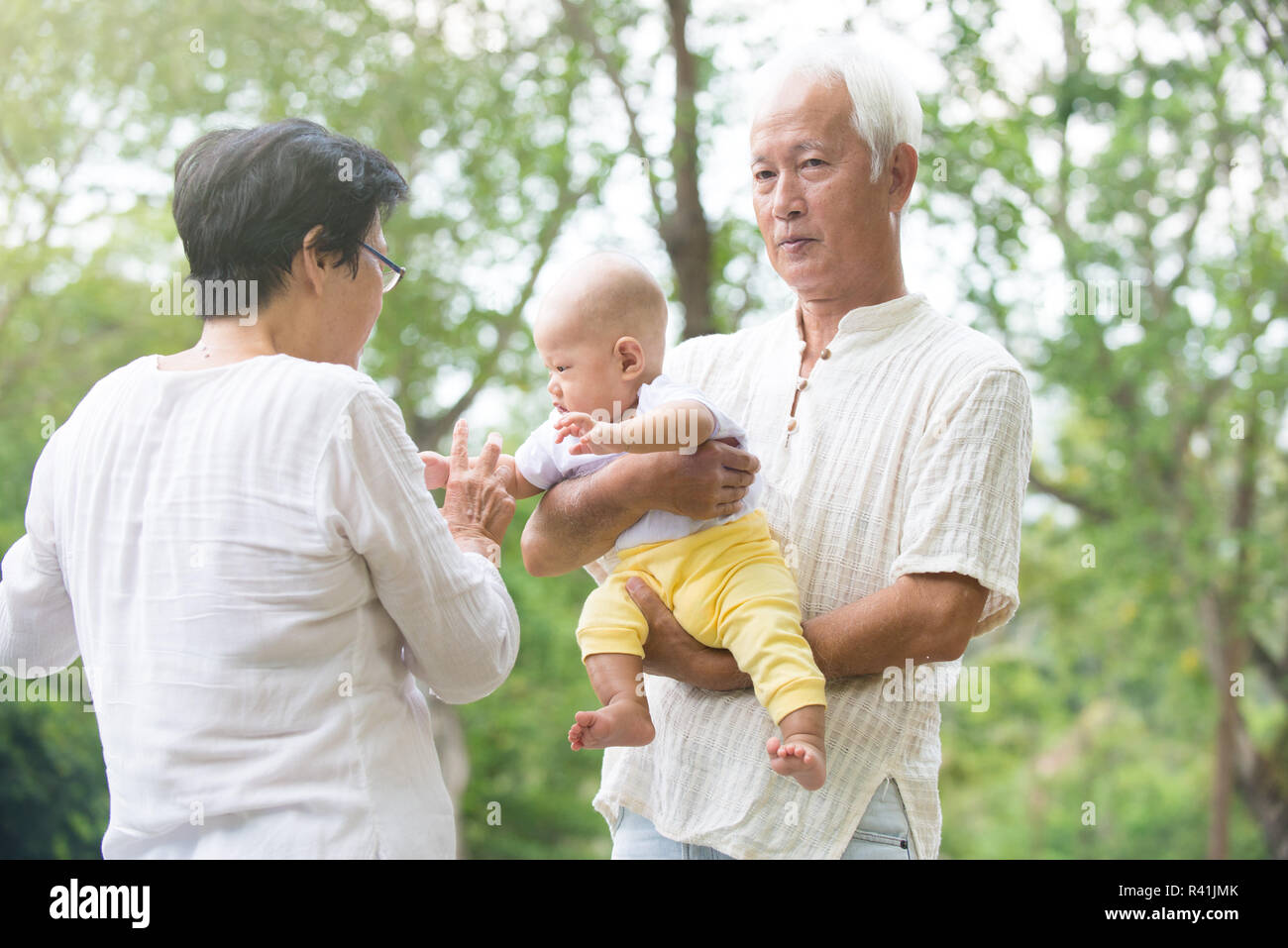 chinese grandfather and grandmother playing with baby grandson at